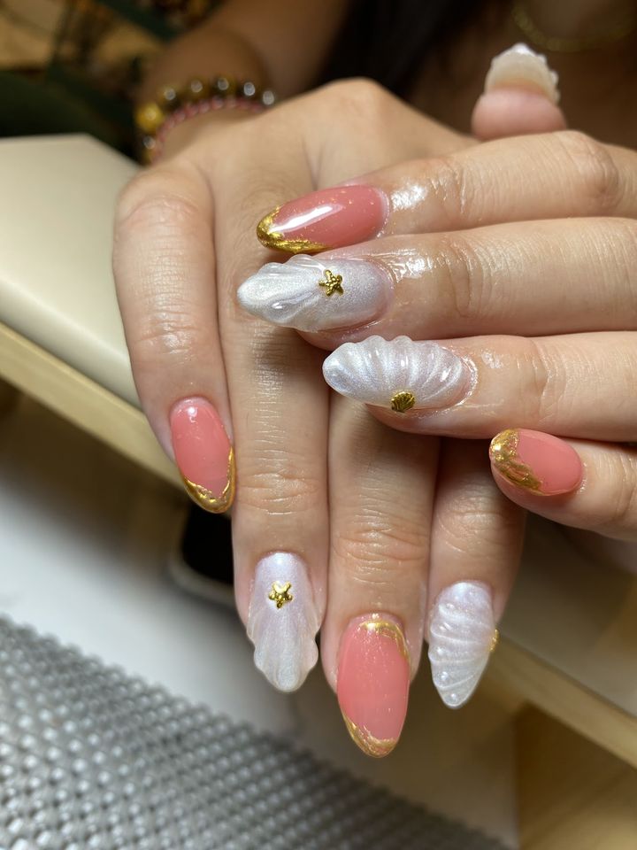 Nail art kerang putih dan koral dengan aksen emas