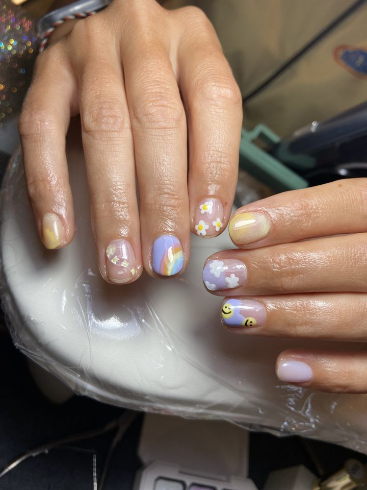 Nail art pastel dengan bunga dan wajah senyum